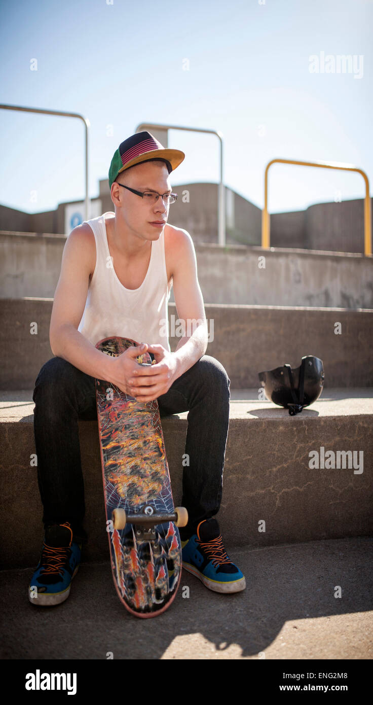 Caucasian man sitting at skate park Stock Photo