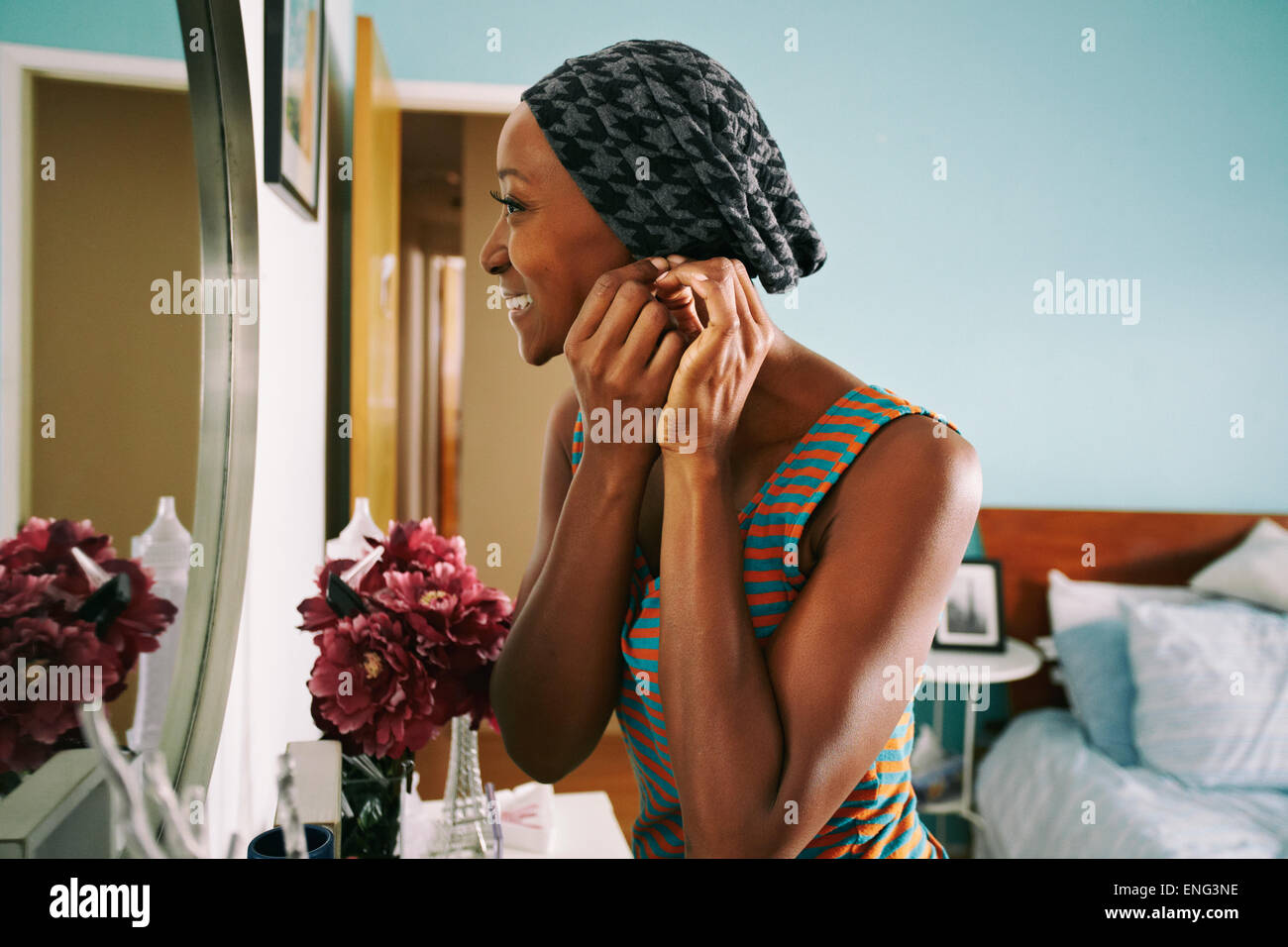 Smiling African American woman attaching earring Stock Photo