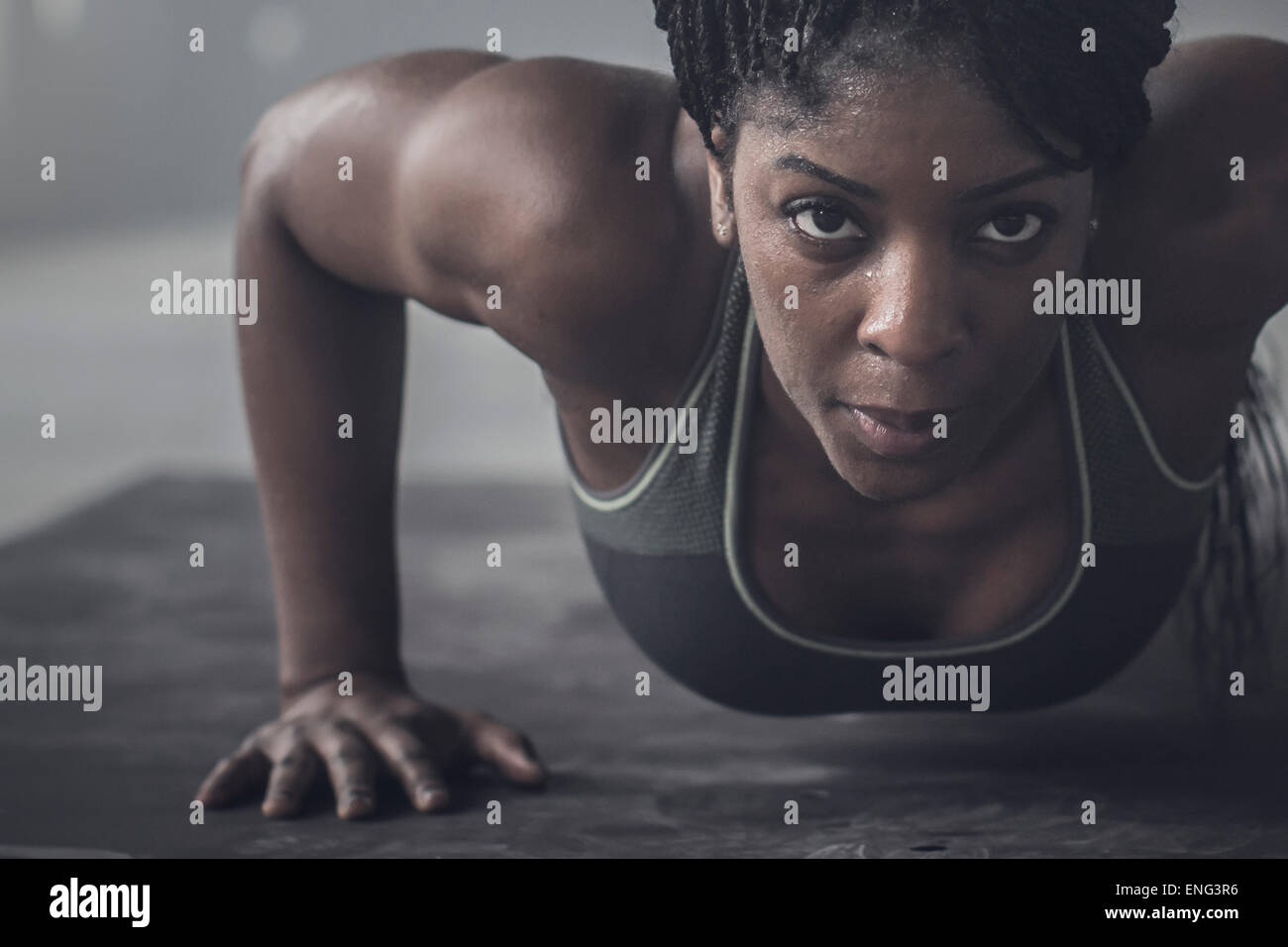 Black woman doing push-ups in dark gym Stock Photo