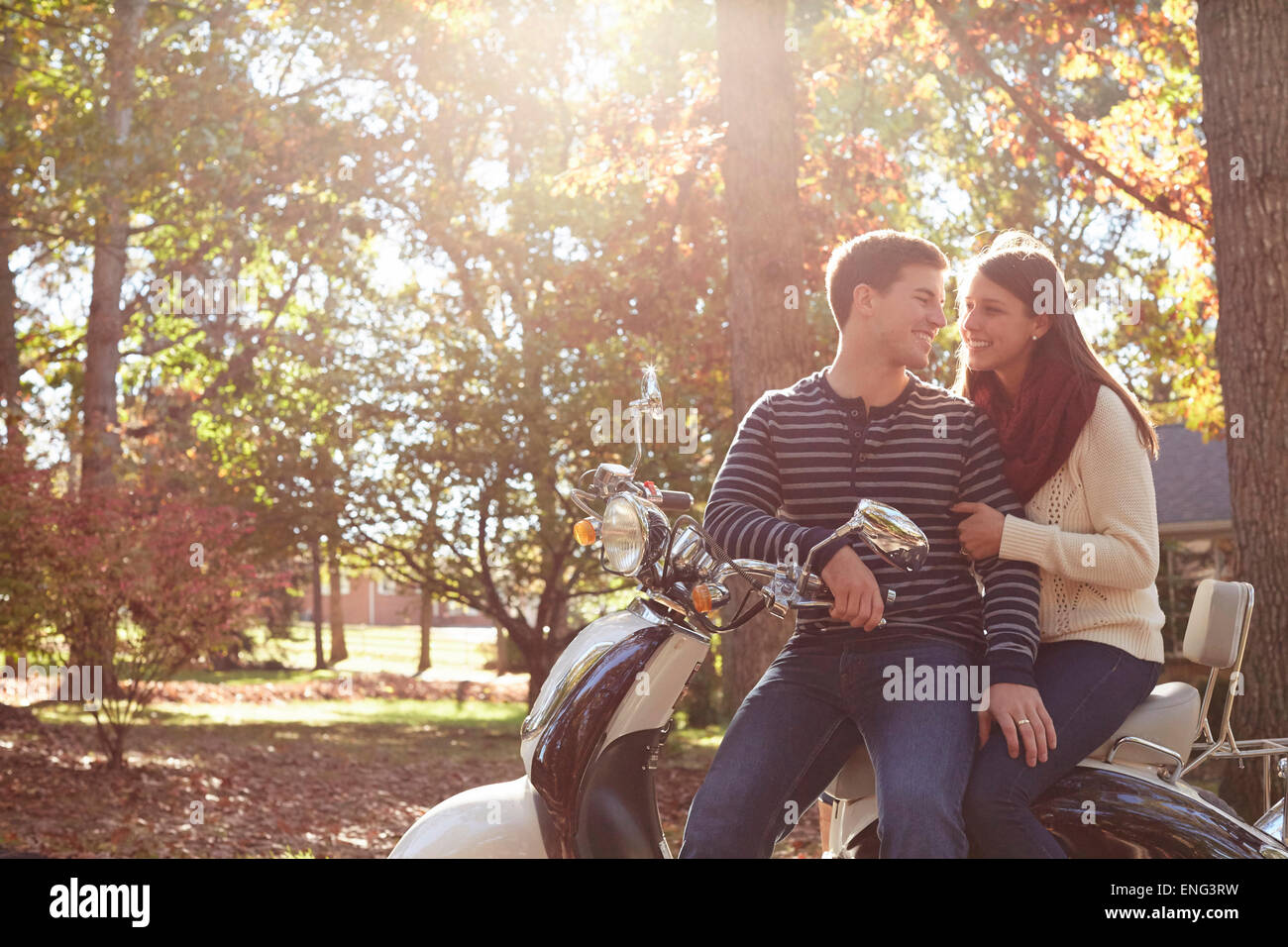 Couple sitting on scooter in park Stock Photo