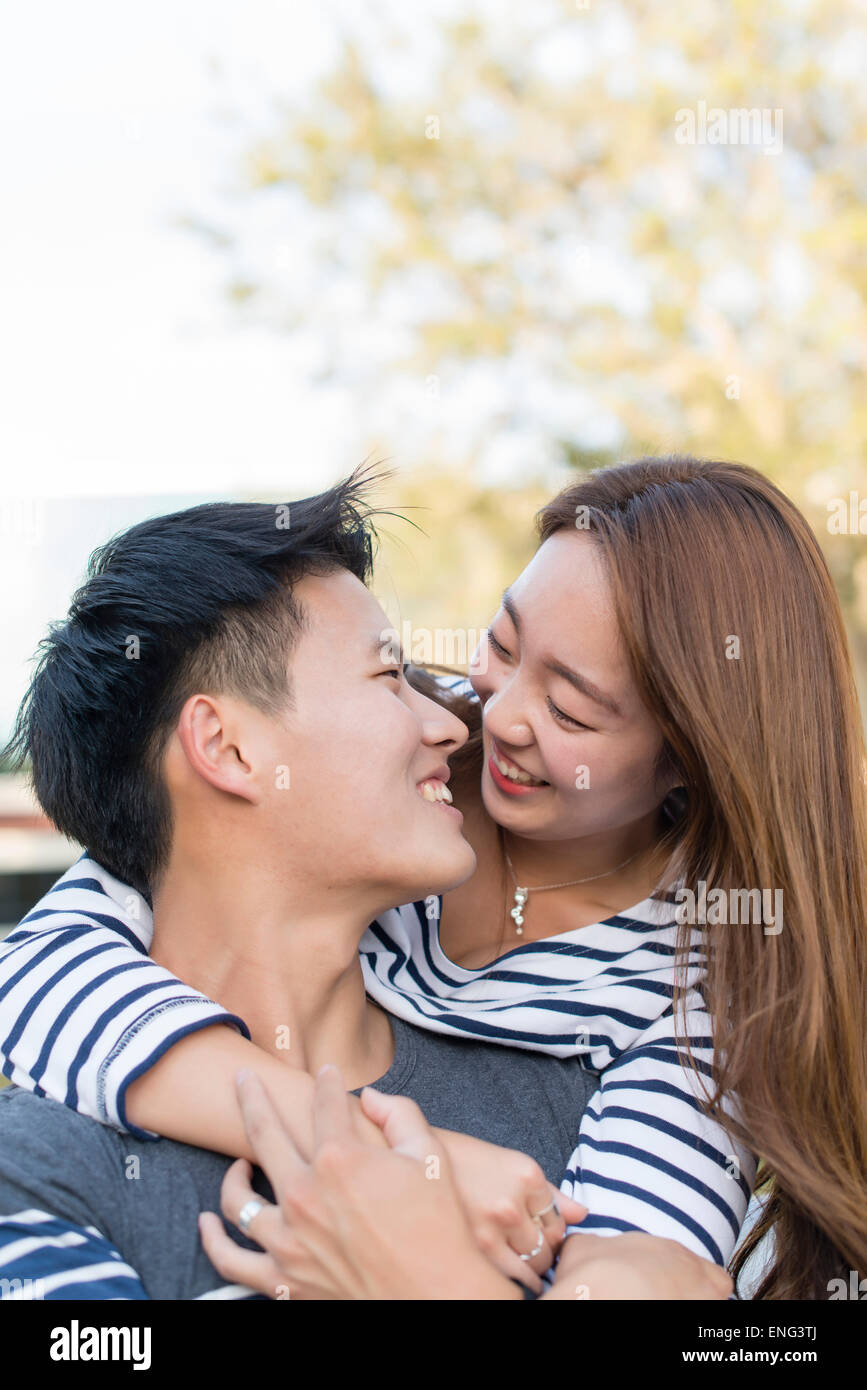 Smiling Korean couple hugging outdoors Stock Photo