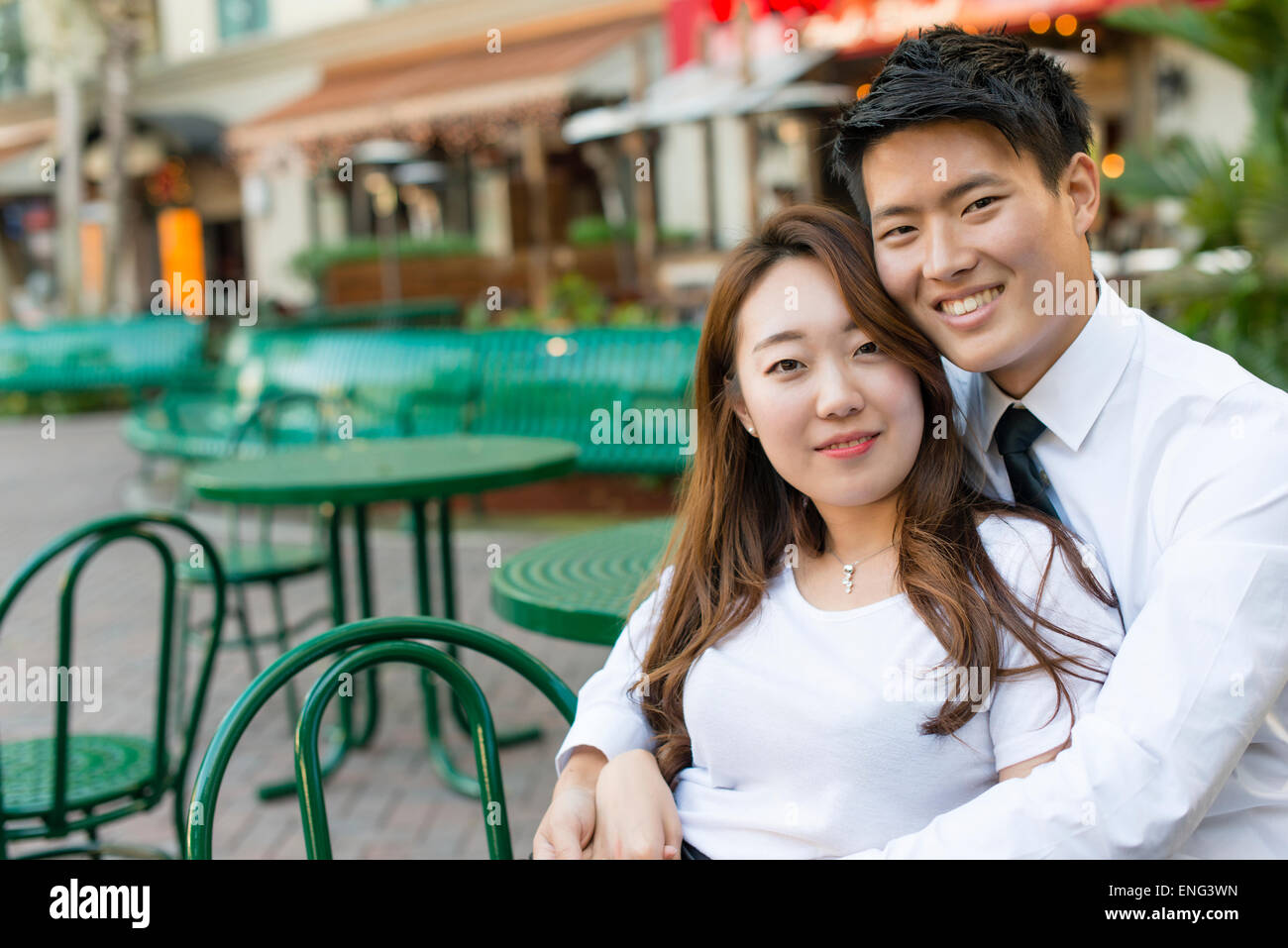 Korean couple hugging at sidewalk cafe Stock Photo