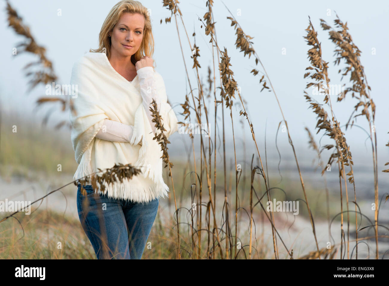 Caucasian woman standing in tall grass on beach Stock Photo