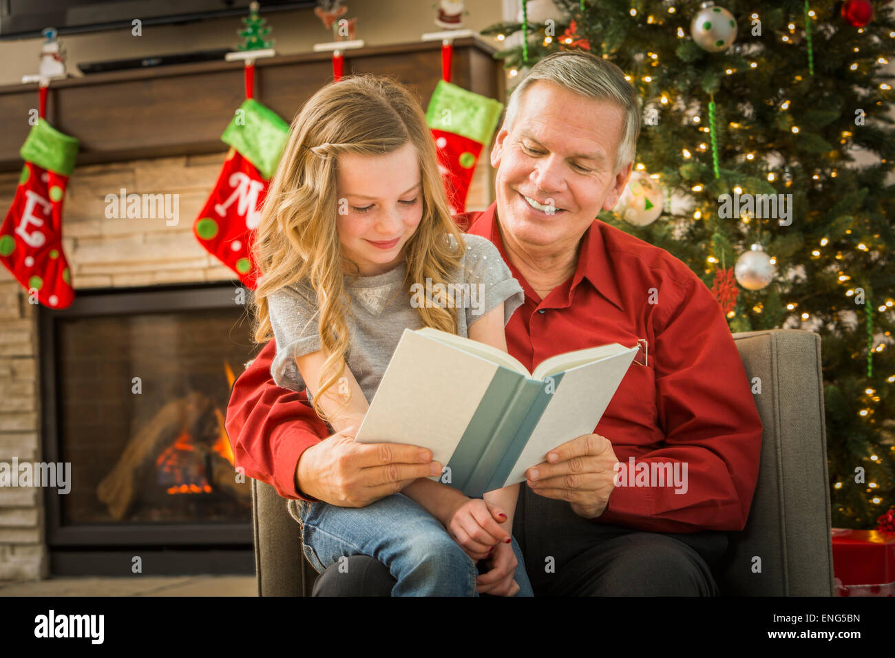 Caucasian grandfather reading to granddaughter at Christmas Stock Photo