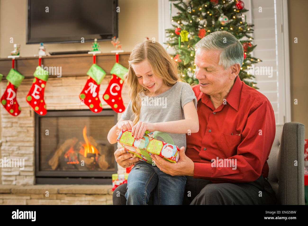 Caucasian grandfather opening Christmas gifts with granddaughter Stock Photo