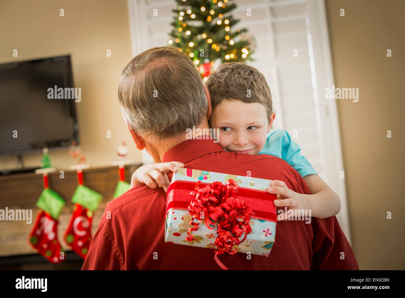 Caucasian grandson hugging grandfather with Christmas gift Stock Photo