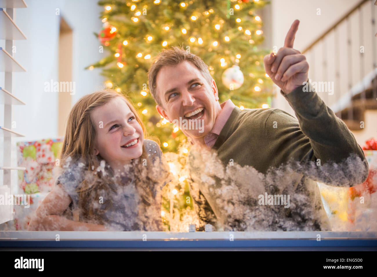 Caucasian father and daughter peering out frosty window at Christmas Stock Photo