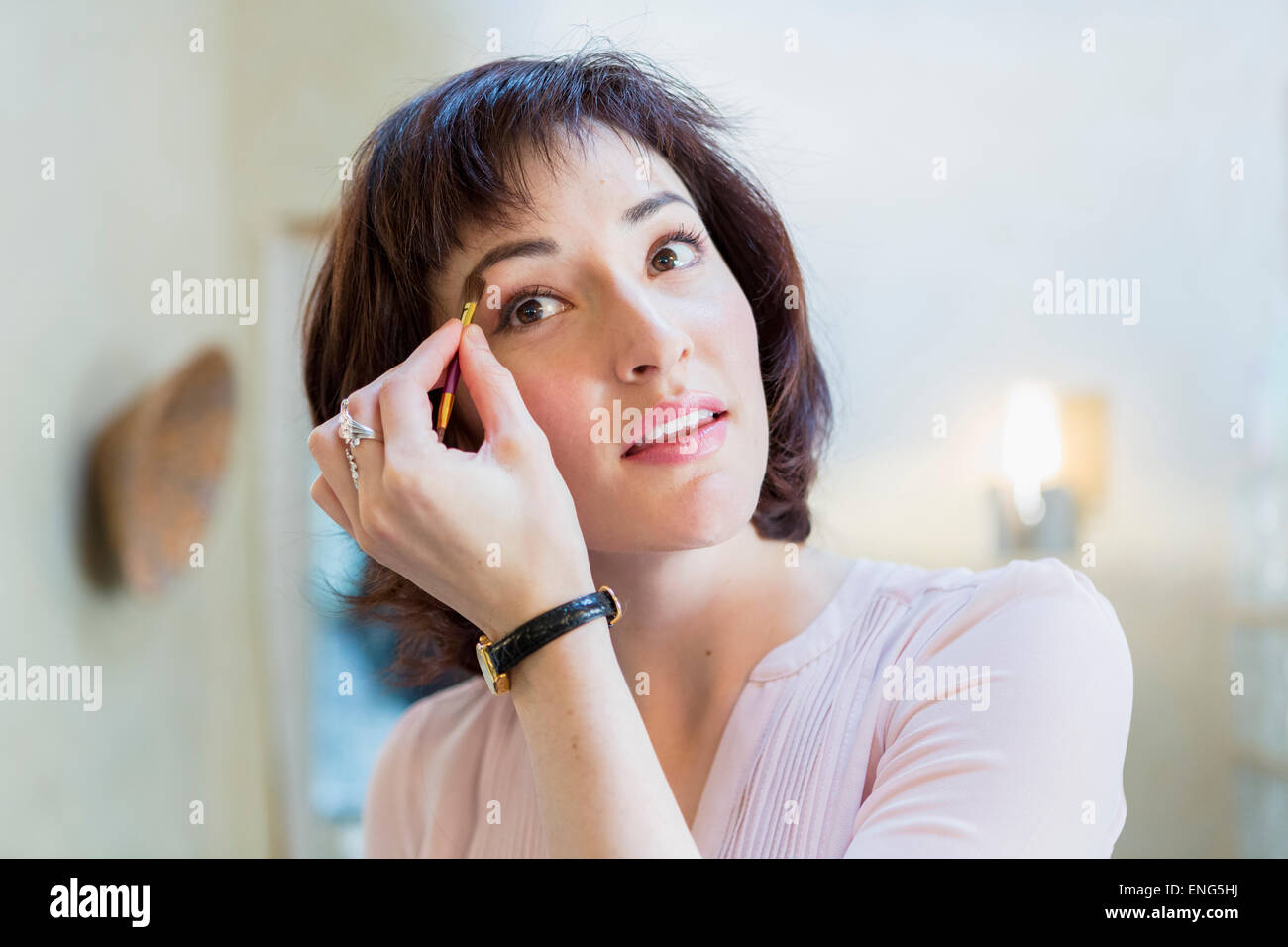 Hispanic woman applying makeup in mirror Stock Photo