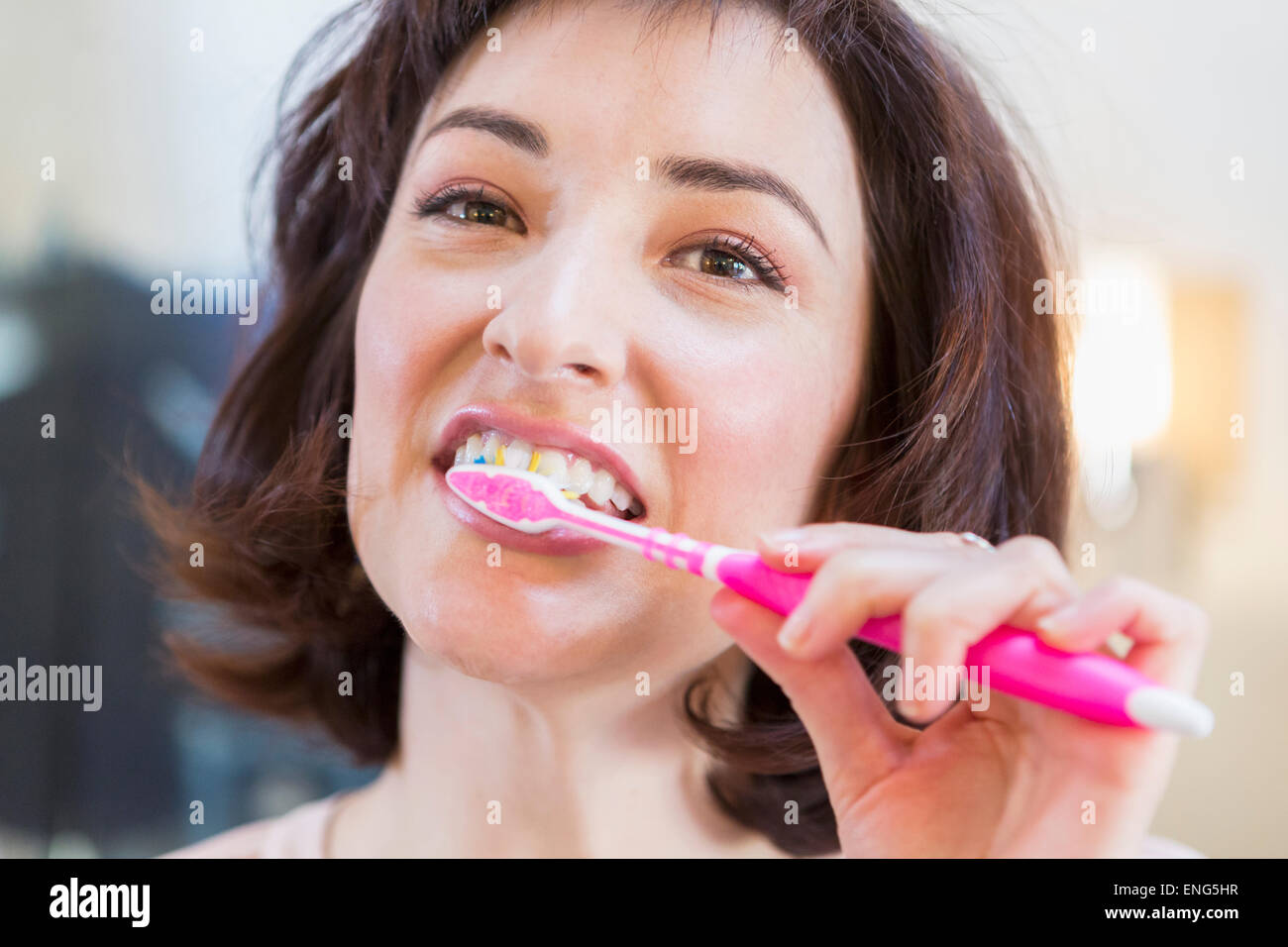 Close up of Hispanic woman brushing her teeth Stock Photo