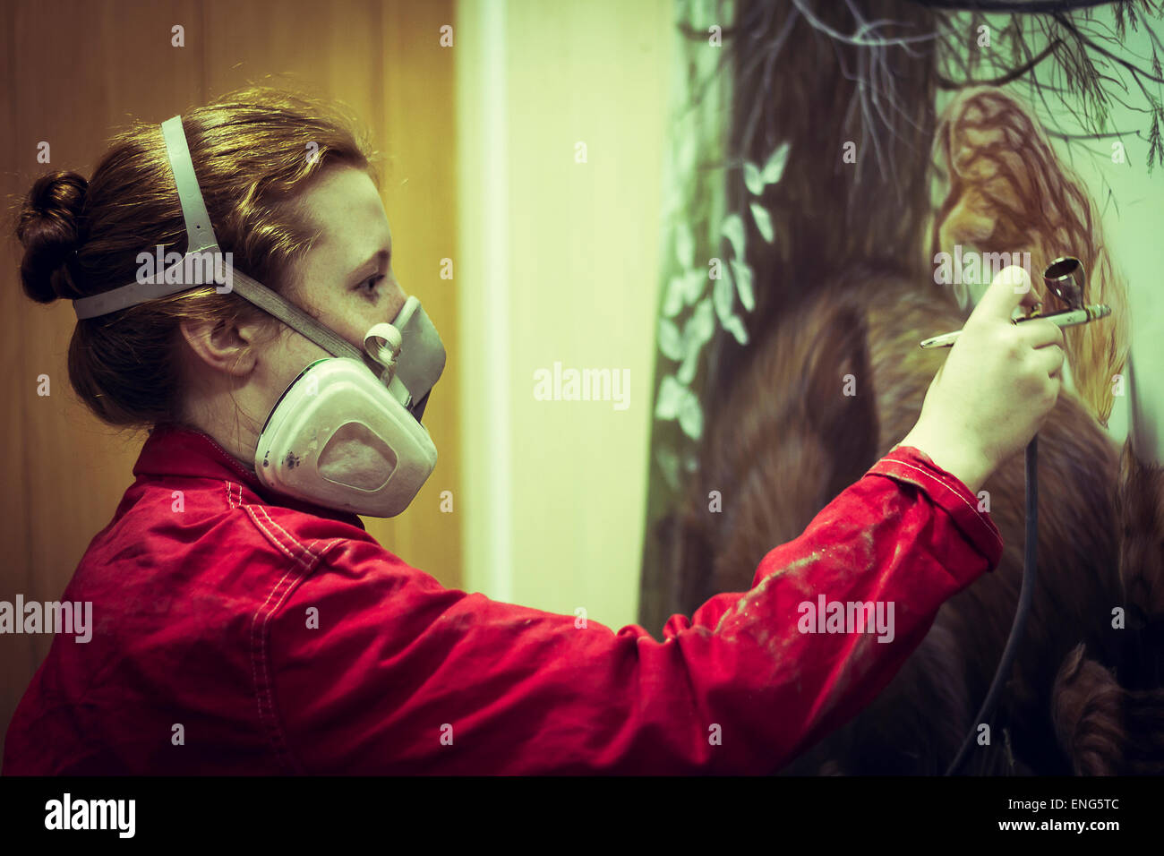 Artist in gas mask airbrushing painting in studio Stock Photo