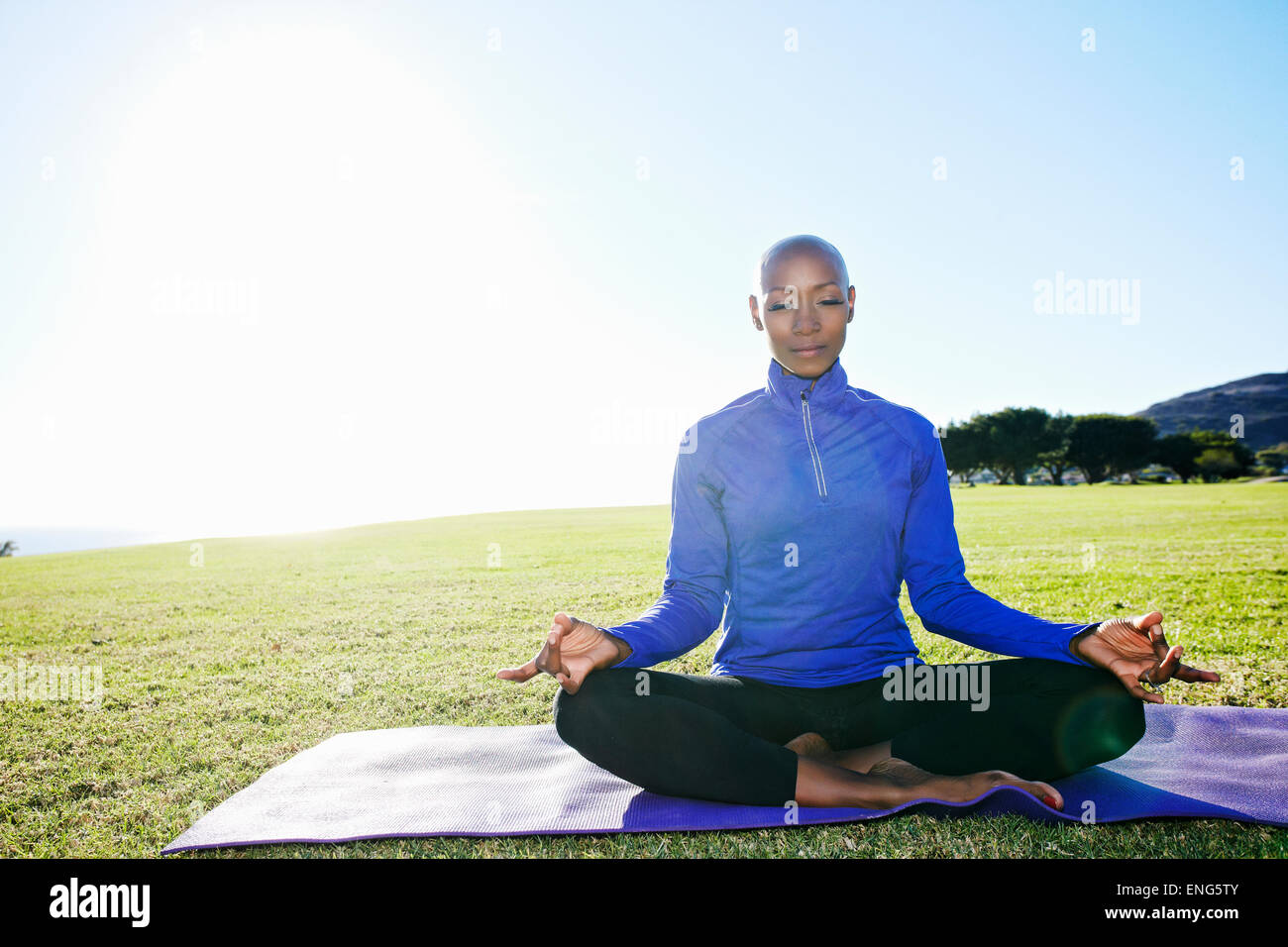 African American woman meditating in park Stock Photo