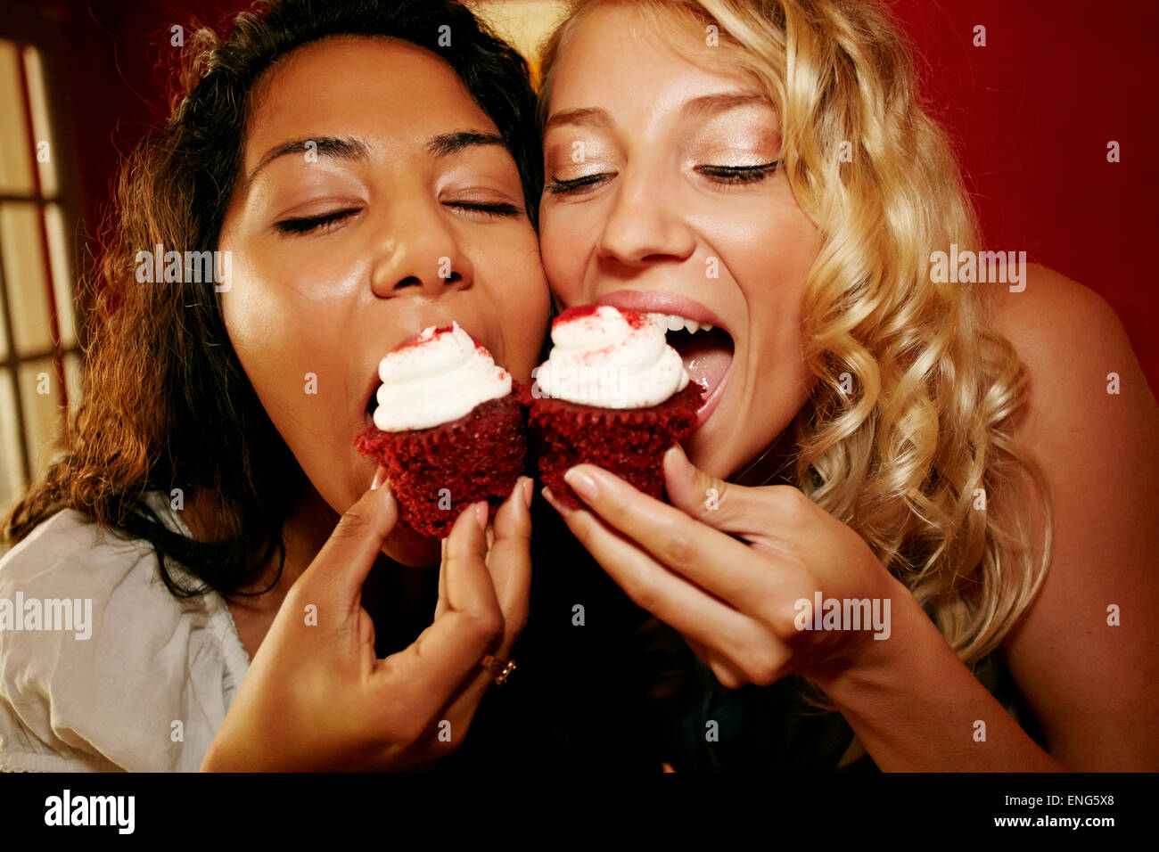 Close up of women eating red velvet cupcakes Stock Photo