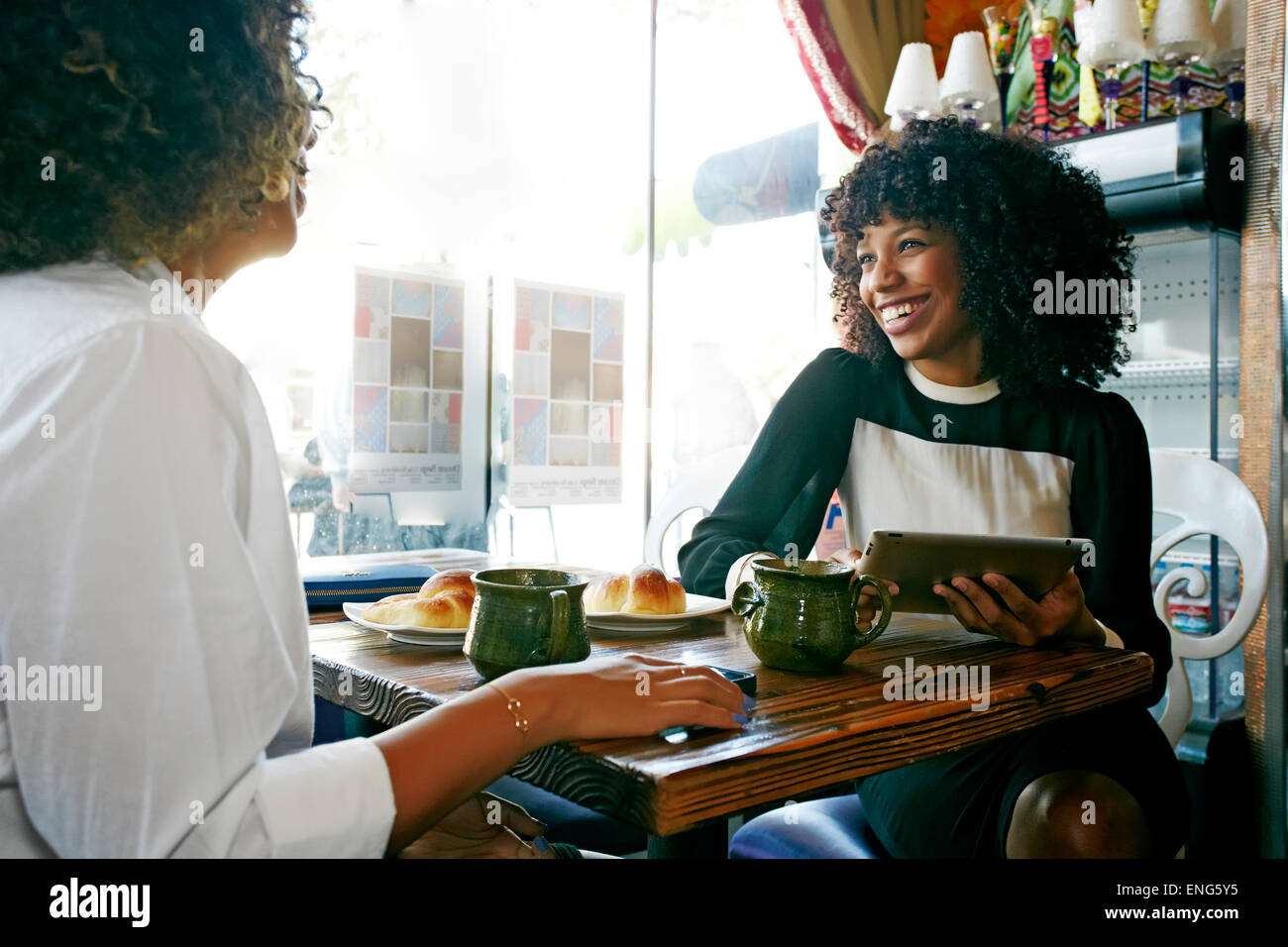 Women using digital tablet and drinking coffee in cafe Stock Photo