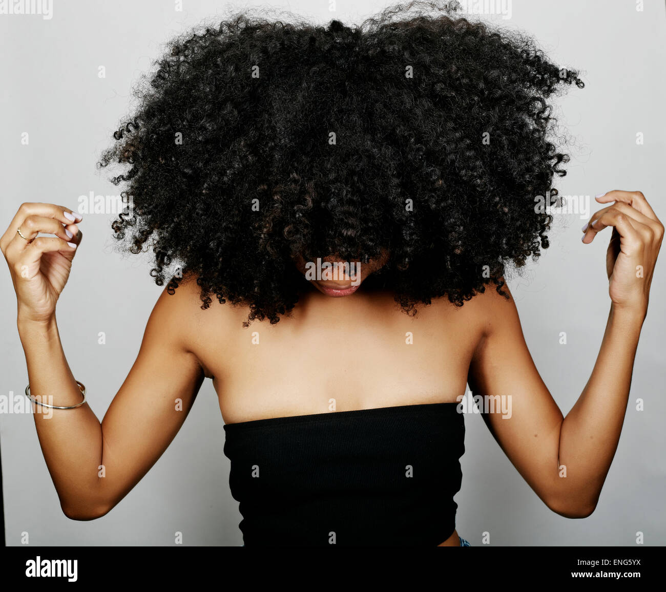 Close up of mixed race woman with curly hair looking down Stock Photo