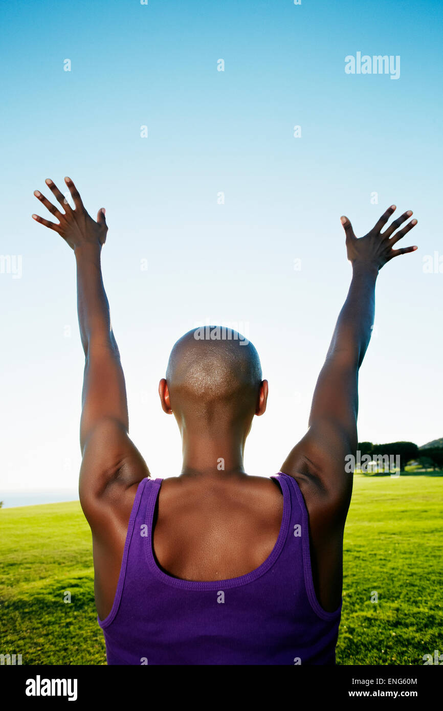 African American woman with arms outstretched in park Stock Photo