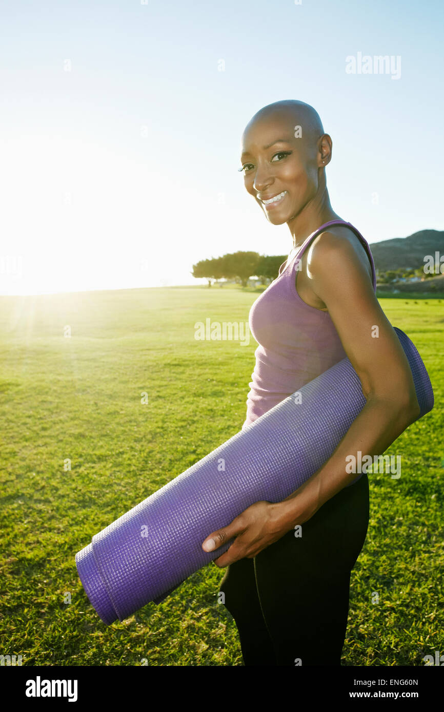 African American woman carrying yoga mat in park Stock Photo Alamy