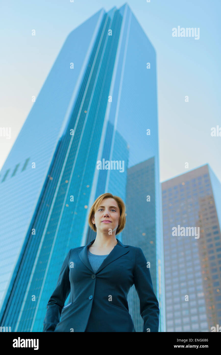 Low angle view of Caucasian businesswoman under high rise buildings Stock Photo