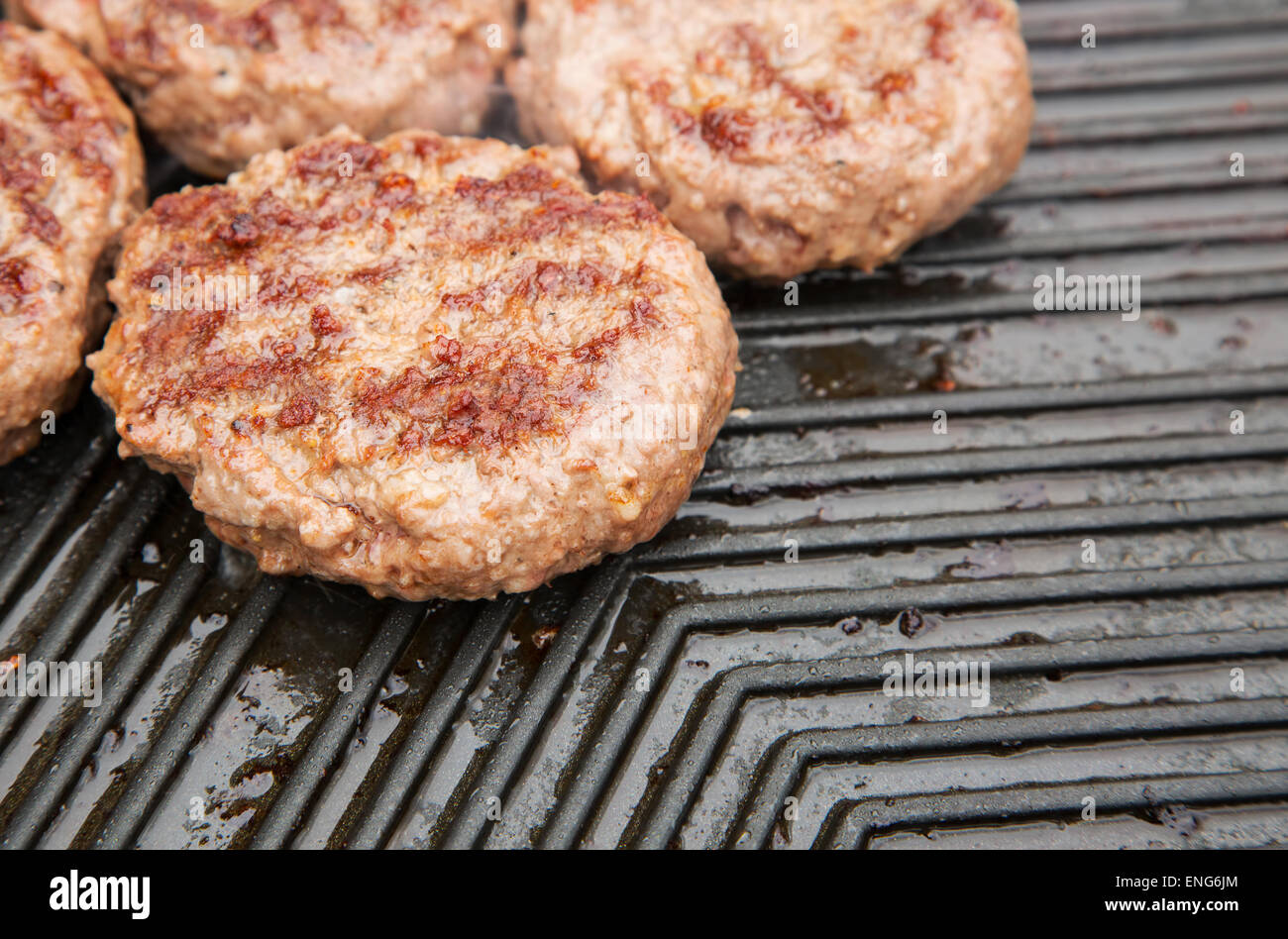 Beef burgers cooking on a metal griddle Stock Photo - Alamy
