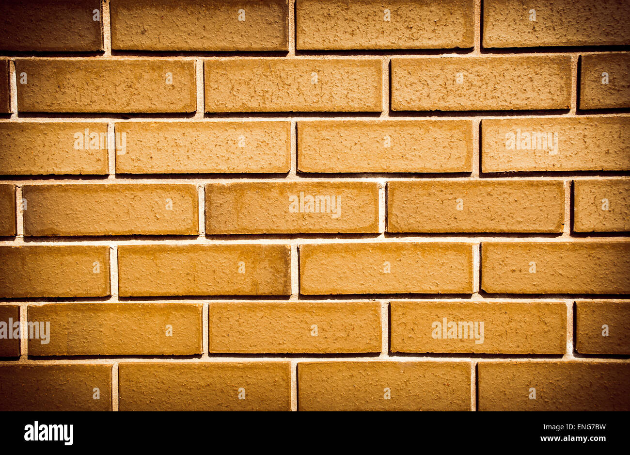Brickwall made up of orange bricks with added saturation and vignetting Stock Photo