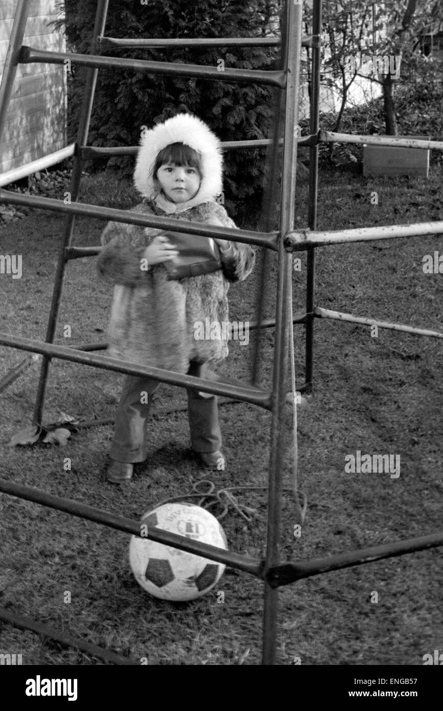 young girl playing inside a climbing frame in a garden in england in the 1970s Stock Photo