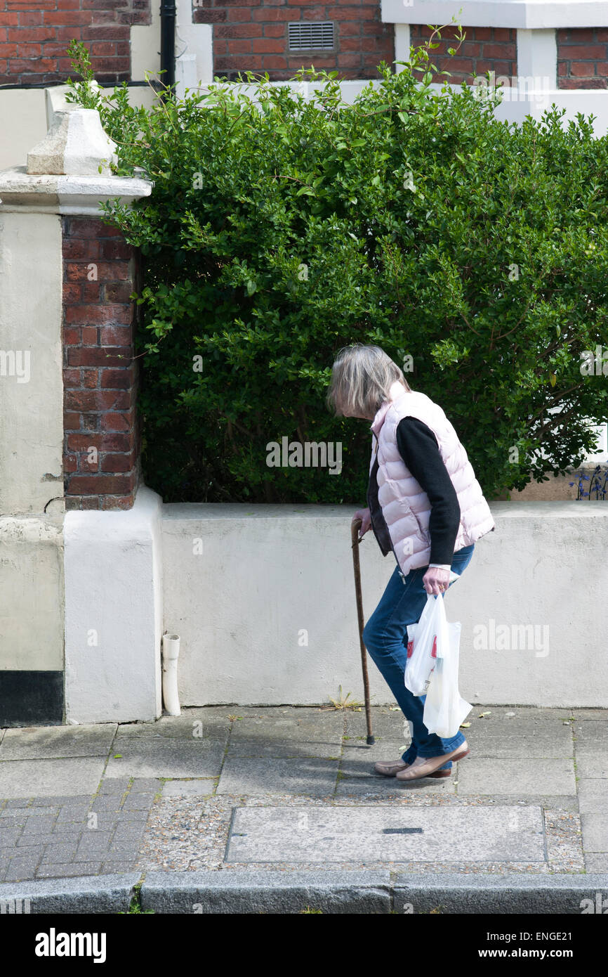 elderly lady with bent back possibly from osteoporosis walking along ...