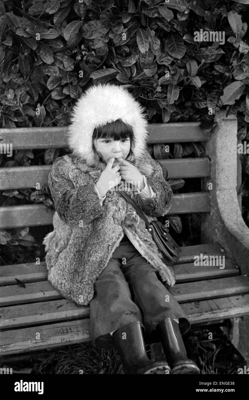 young girl sat on a park bench whistling in the 1970s england uk Stock Photo