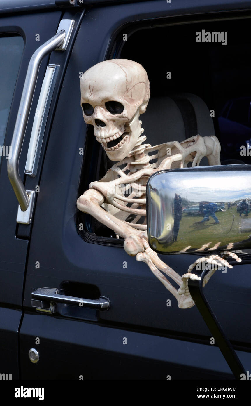 Been waiting long? A skeleton leans from the window of a large SUV stuck in a long traffic jam or the devil rides out! Stock Photo