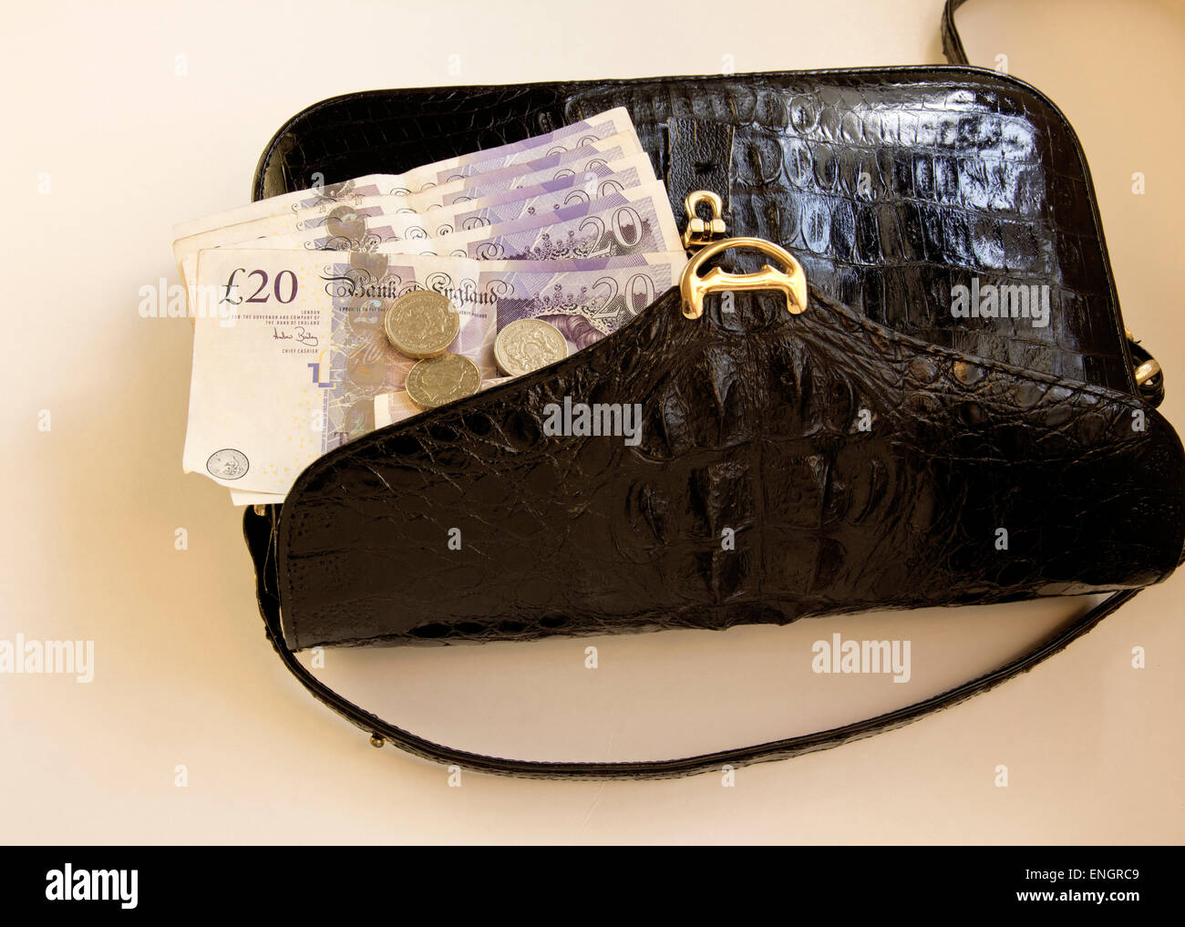 £20 pound notes and pound coins in a Black coloured Crocodile Skin Handbag. Stock Photo