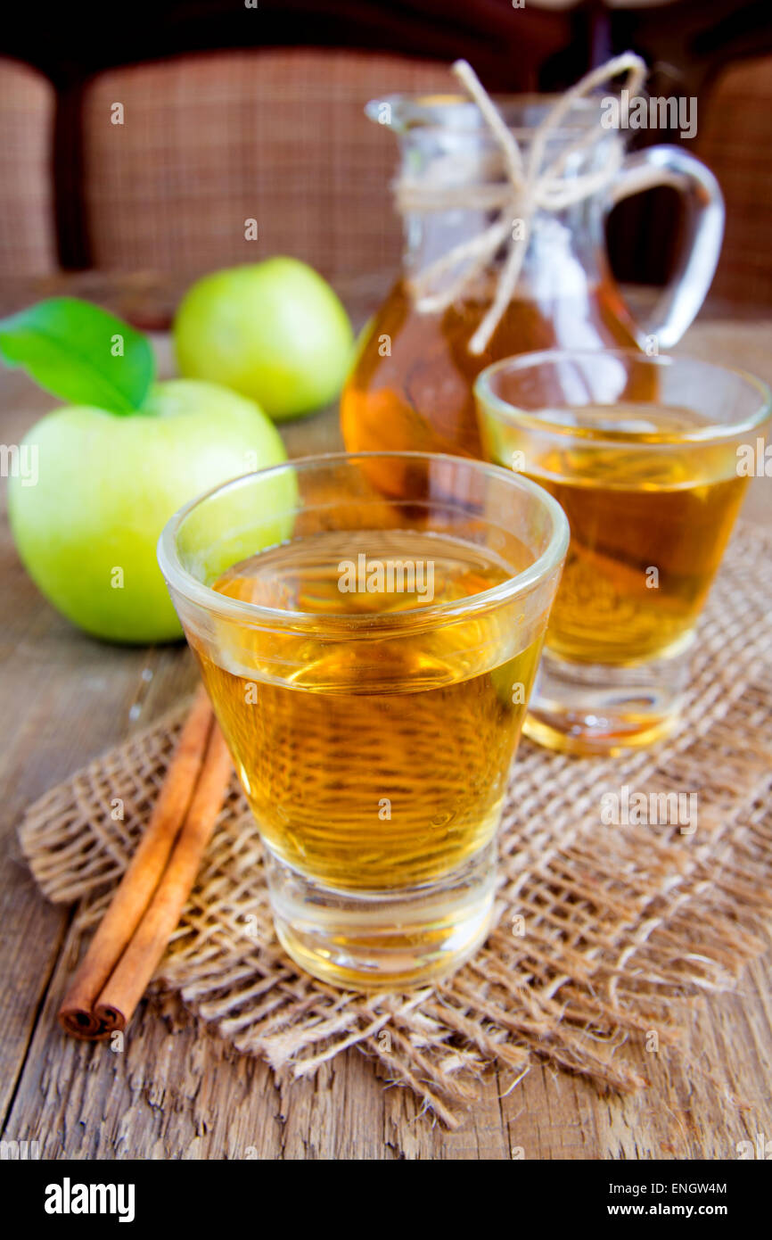 Apple tea (cider) with cinnamon sticks, green apples and leaves on rustic wooden background Stock Photo