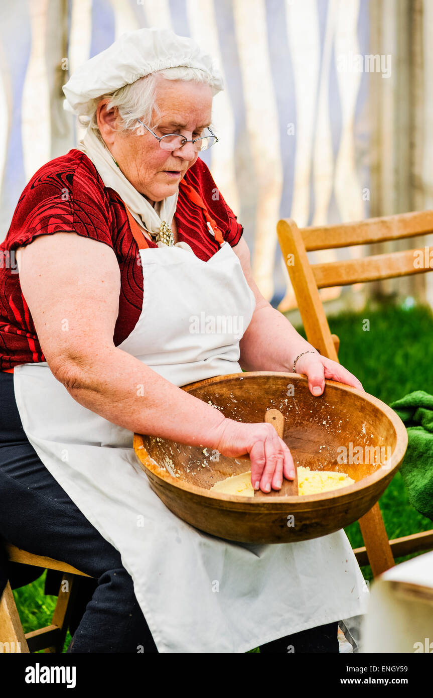 An elderly Irish lady uses a paddle to hand-make butter. Stock Photo
