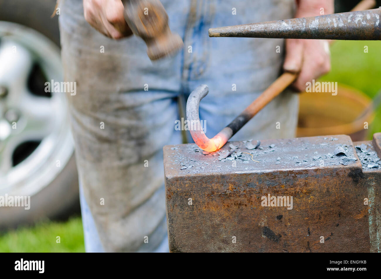 Blacksmith beats a red-hot iron bar into shape using a hammer Stock Photo