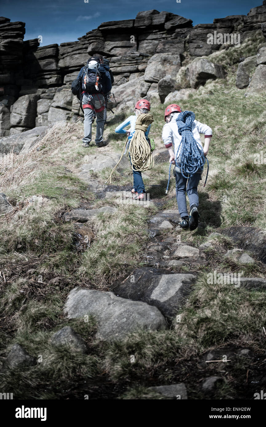A young boy and girl on a climbing expedition follow their instructor on a path Stock Photo