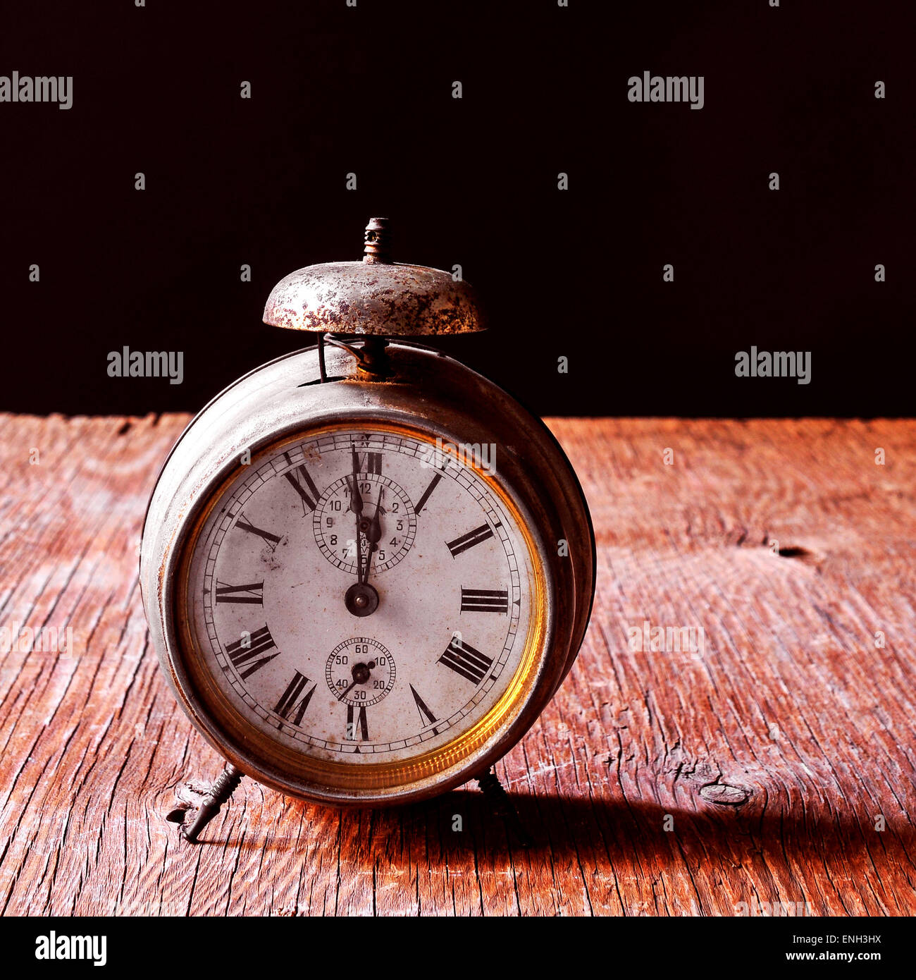 a rusty old alarm clock on a rustic wooden table, with a black