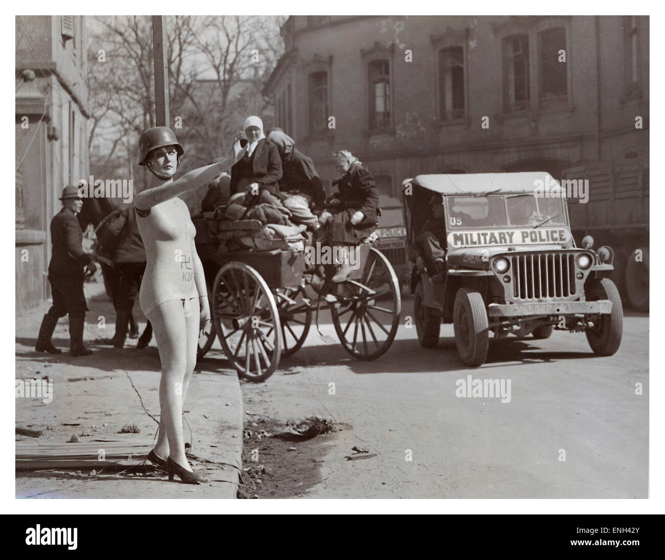 OCCUPIED BERLIN WW2 Dark humour image in post war 1945 Berlin of helmeted shop mannequin giving Hitler salute with American jeep and refugees behind Stock Photo