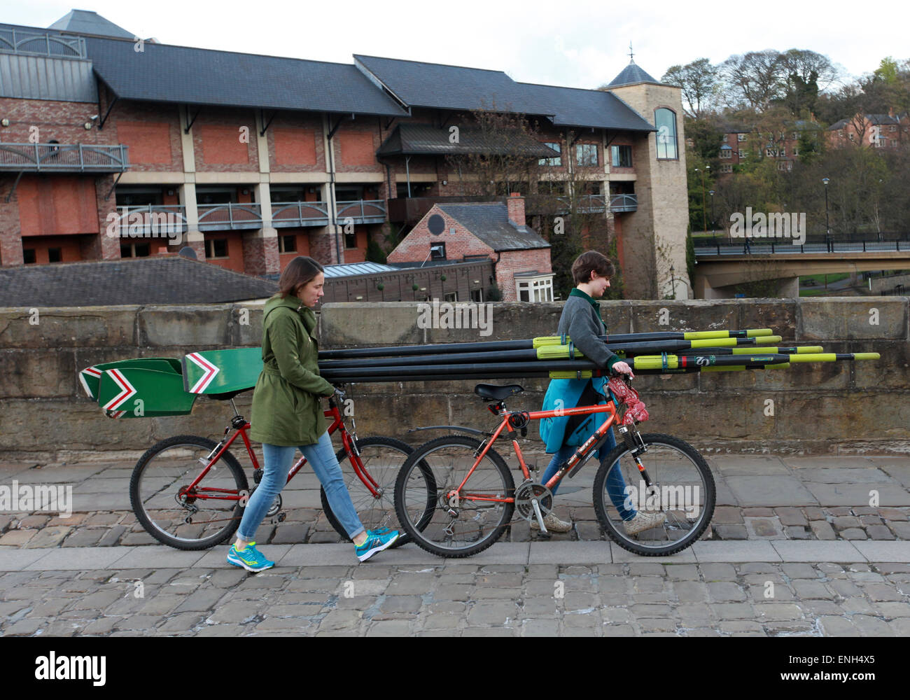 Rowers carry their oars on their bikes over Elvet Bridge in Durham Stock Photo