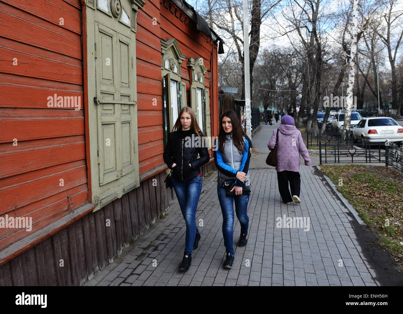Beautiful Russian women walking by an old traditional wooden house in Irkutsk. Stock Photo