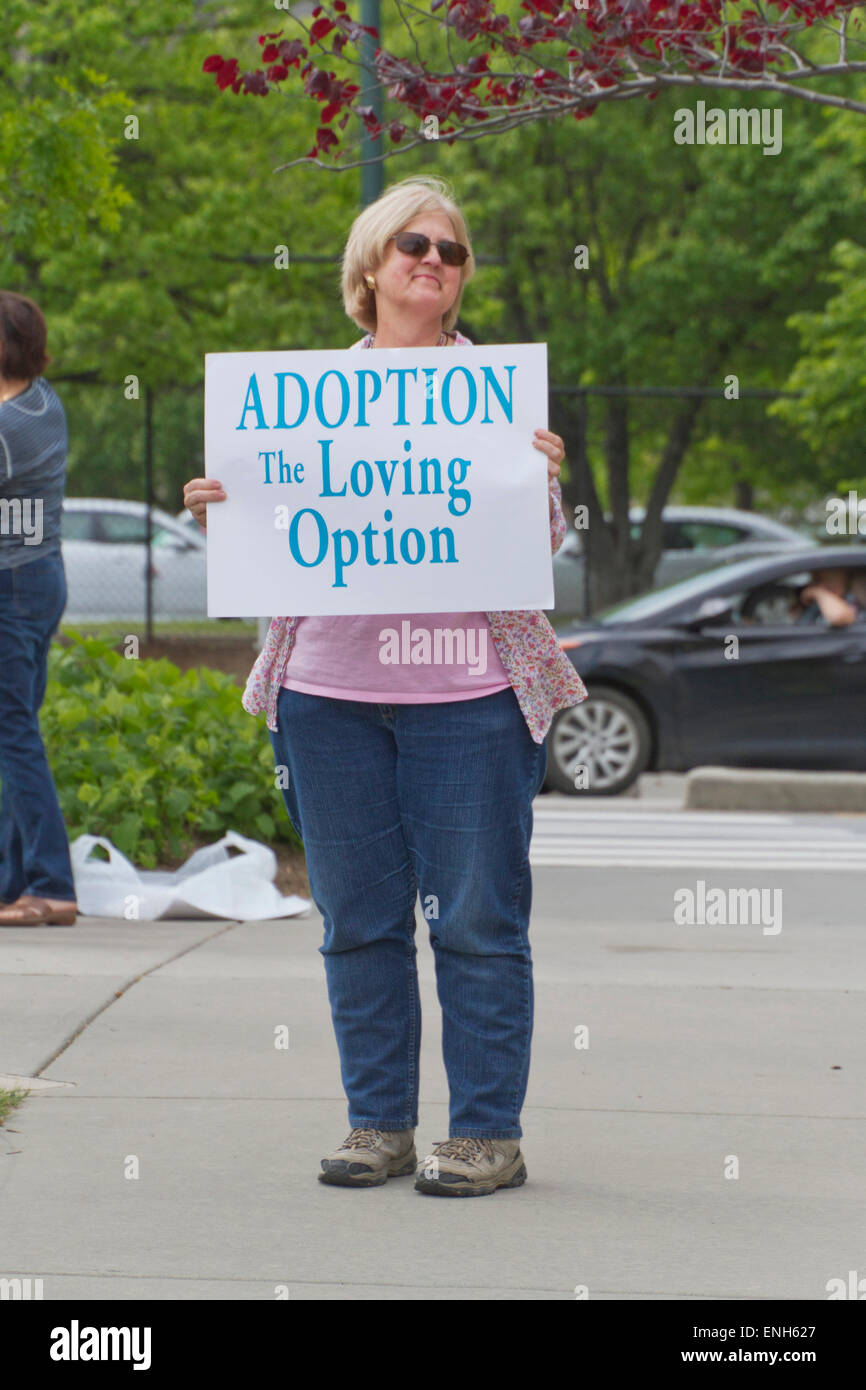 Asheville, North Carolina, USA - May 4, 2015:  A middle aged woman holds an anti-abortion sign urging adoption instead at a rally protesting North Carolina abortion Bill #465, which requires a much longer waiting period for women seeking abortions on May 4, 2015 in downtown Asheville, NC Credit:  Judith Bicking/Alamy Live News Stock Photo
