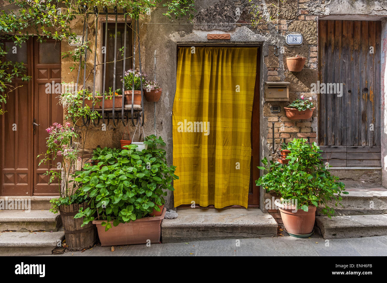 Bright yellow striped curtain in doorway near front entrances to rustic residences in Pitigliano, Grosseto Province, Italy Stock Photo