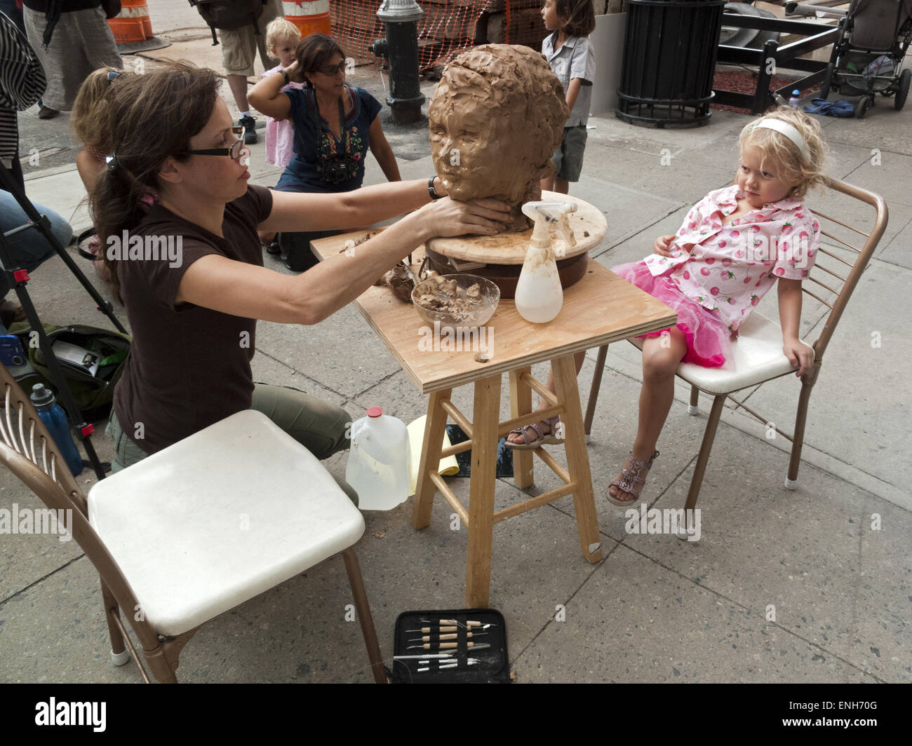 Artist sculpting bust of young girl at Brooklyn Bridge Park in DUMBO in