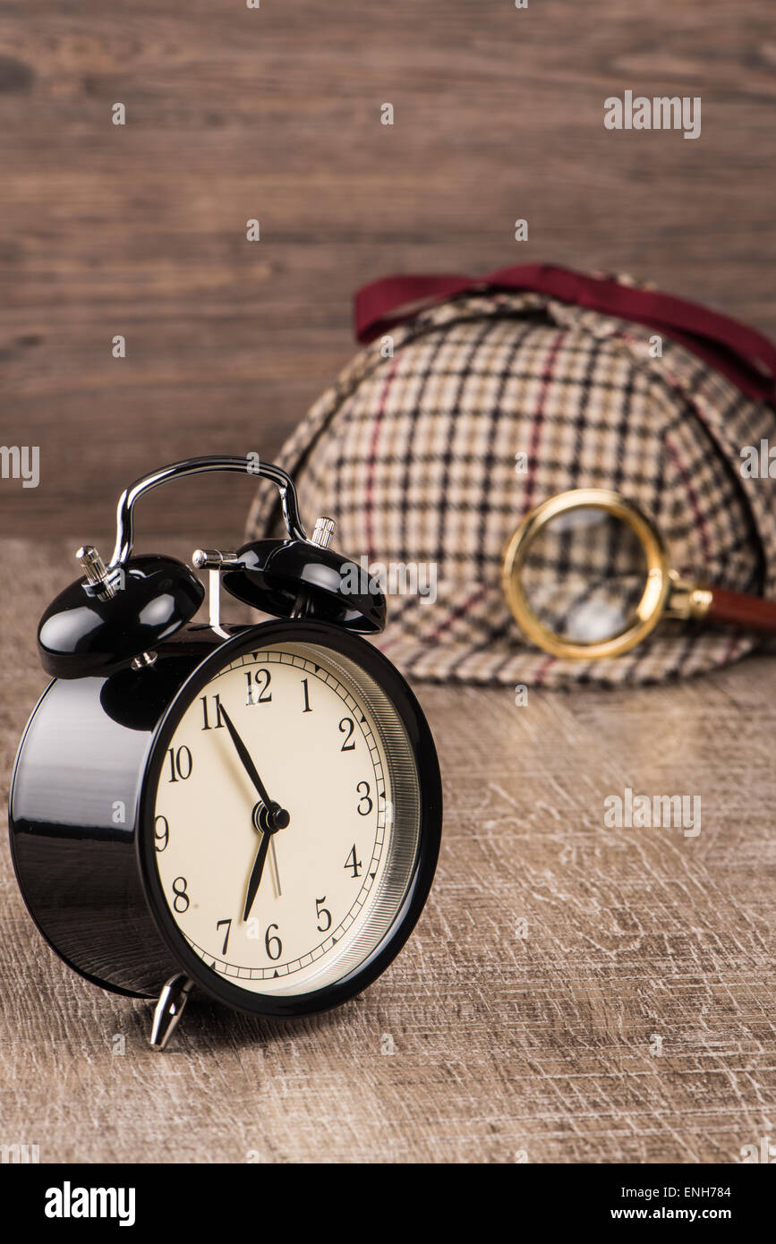 Deerstalker or Sherlock Hat and magnifying glass on Old Wooden table. Stock Photo