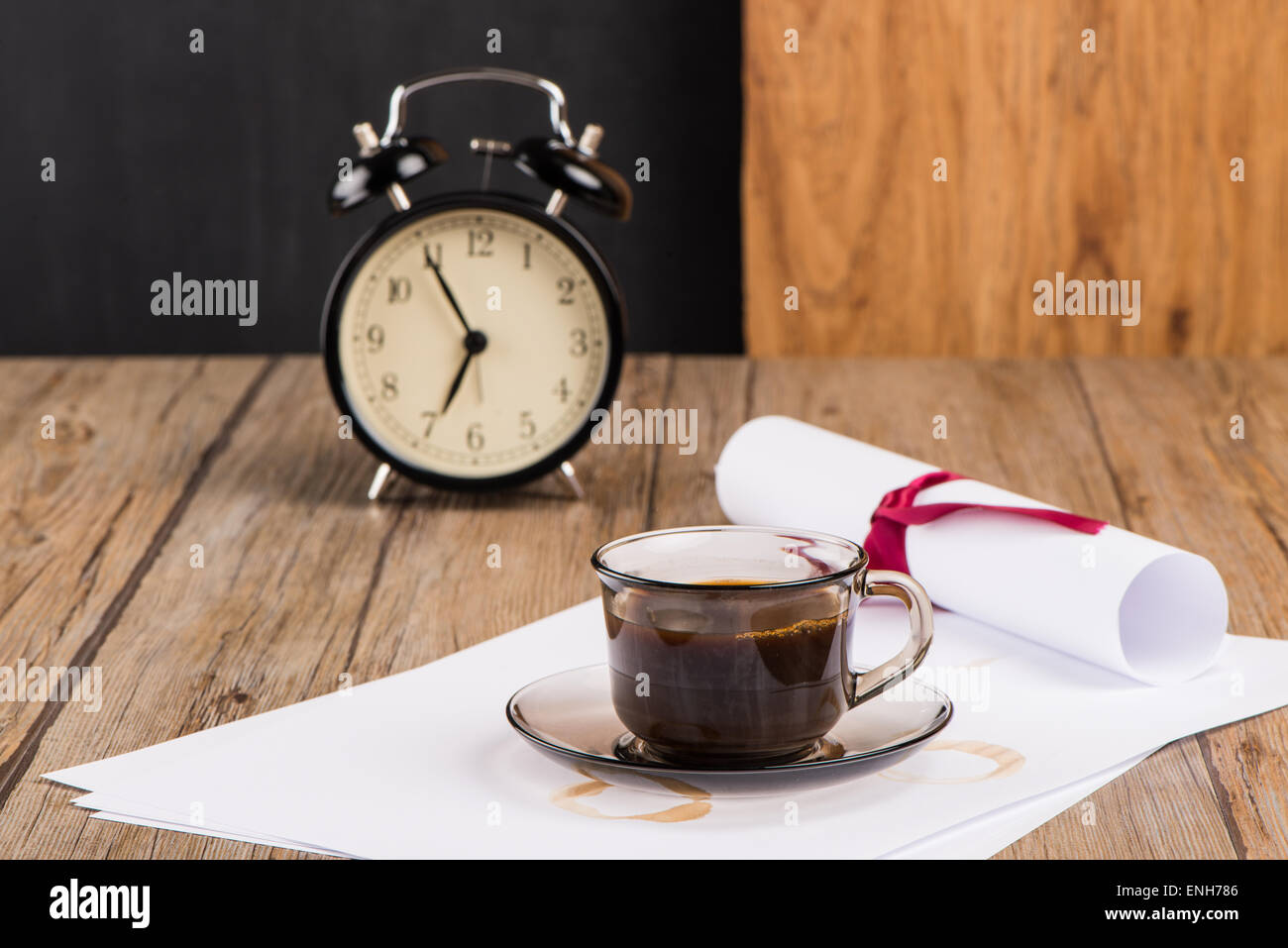 Old clock, hat, coffee and paper sheets on old Wooden table. Stock Photo