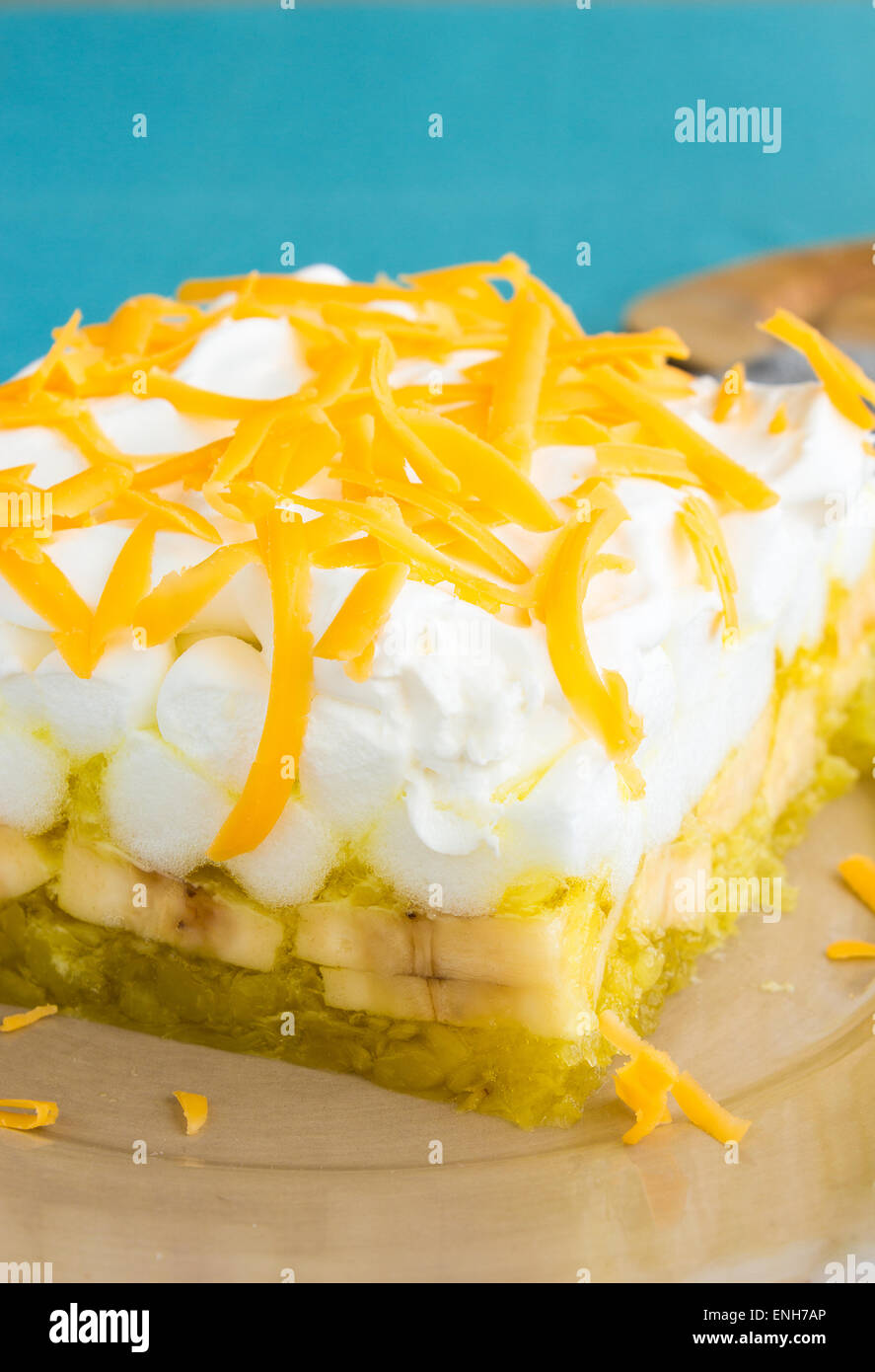 Hawaiian salad made with lemon jello, pineapple, banana, mini marshmallows, topped with whipped