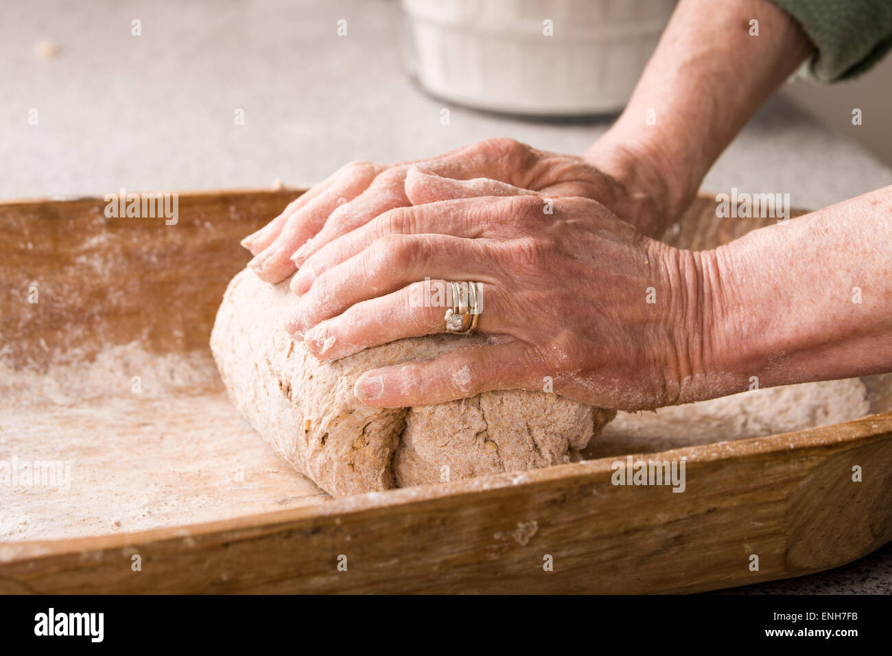Woman kneading dough in a dough trough until it is smooth and elastic