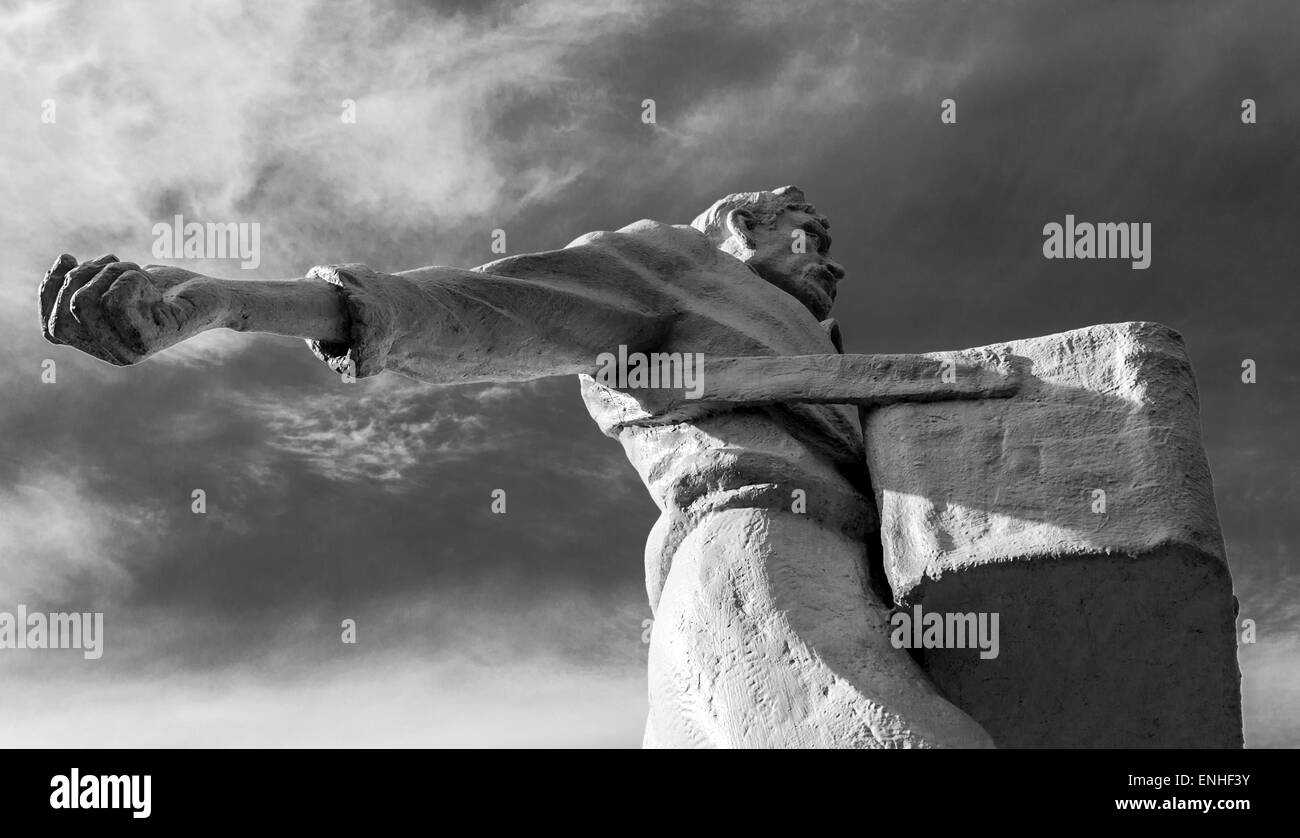 White stone farmer broadcasting seeds against a blue sky in black and white Stock Photo