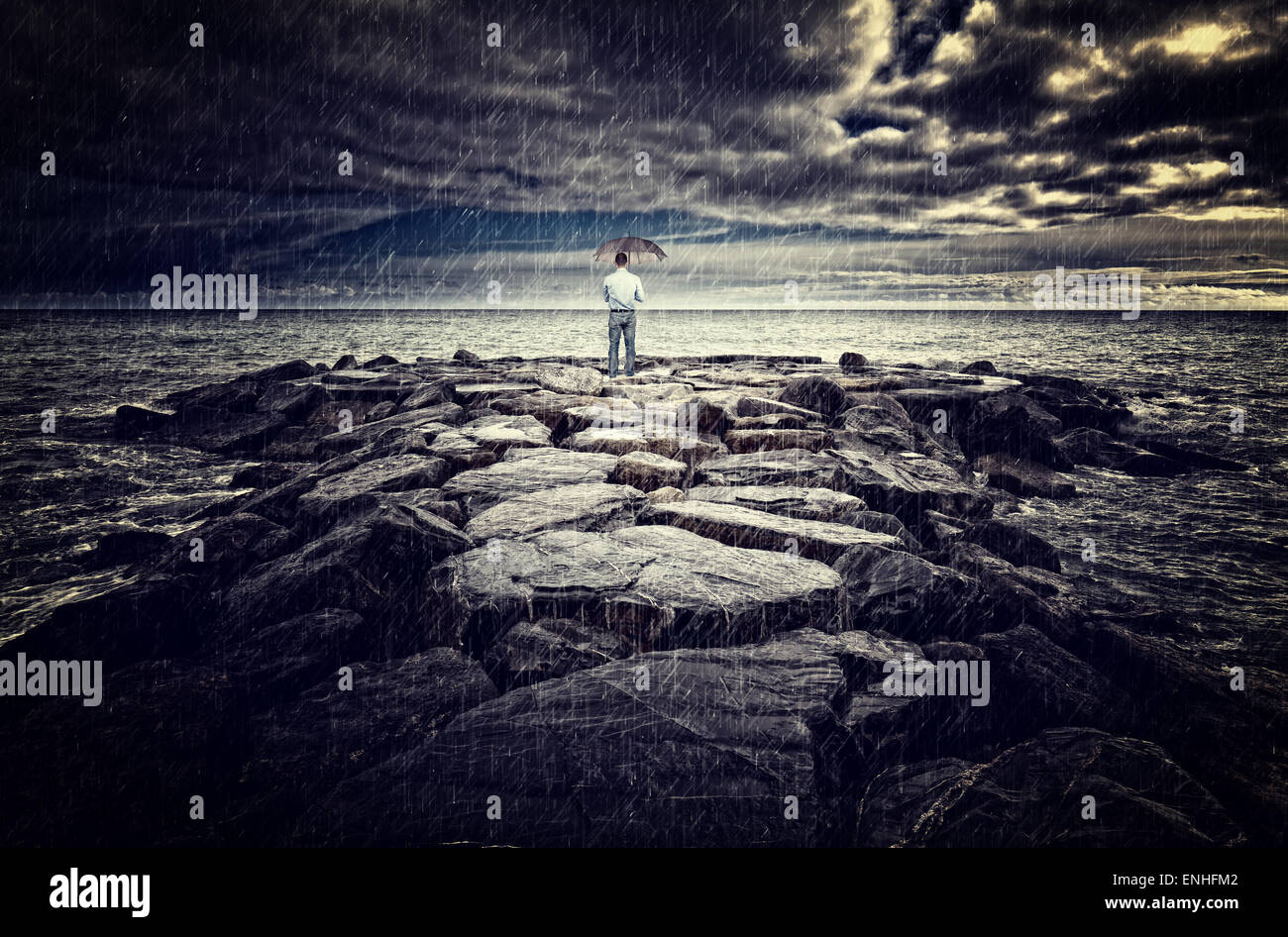 man with umbrella on sea rock bad weather Stock Photo