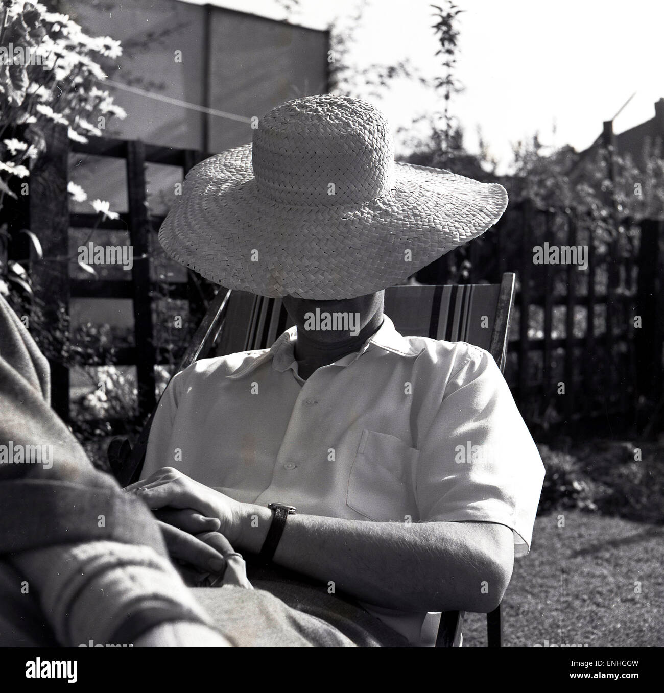 1950s, historical, mystery man sitting outside in a deck chair with a large sun hat covering his face and head. Stock Photo