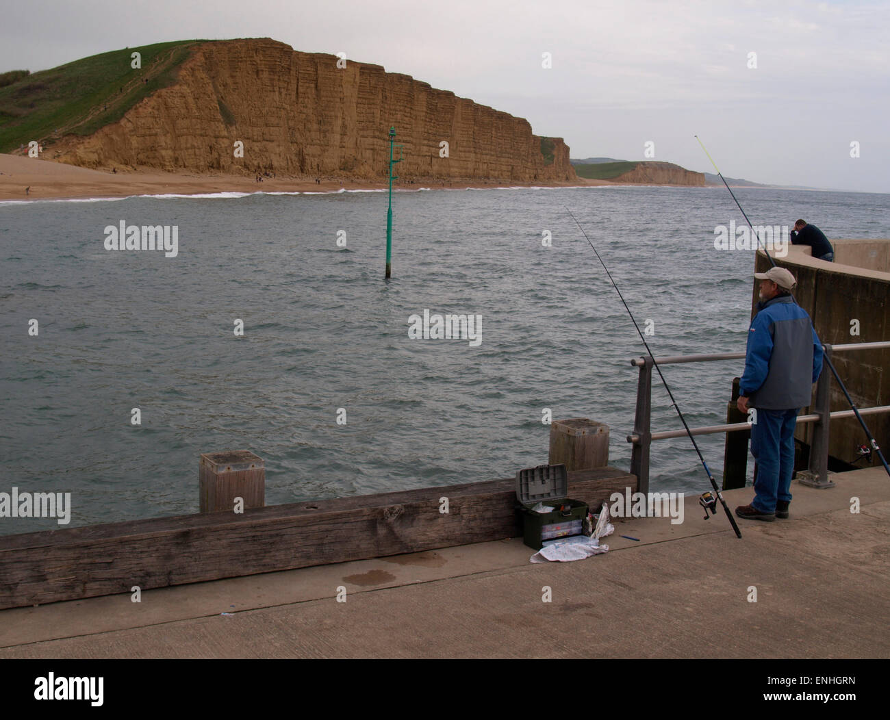 Man fishing from the harbour wall, West Bay, Dorset, UK Stock Photo - Alamy