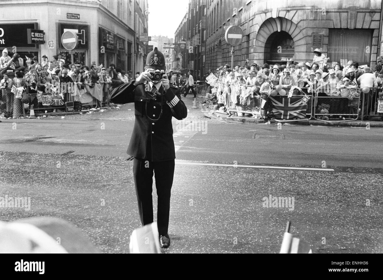 Wedding day of Prince Charles & Lady Diana Spencer, 29th July 1981. Picture: Helpful on duty Policeman takes a picture of the crowd lining the procession route in London. Stock Photo
