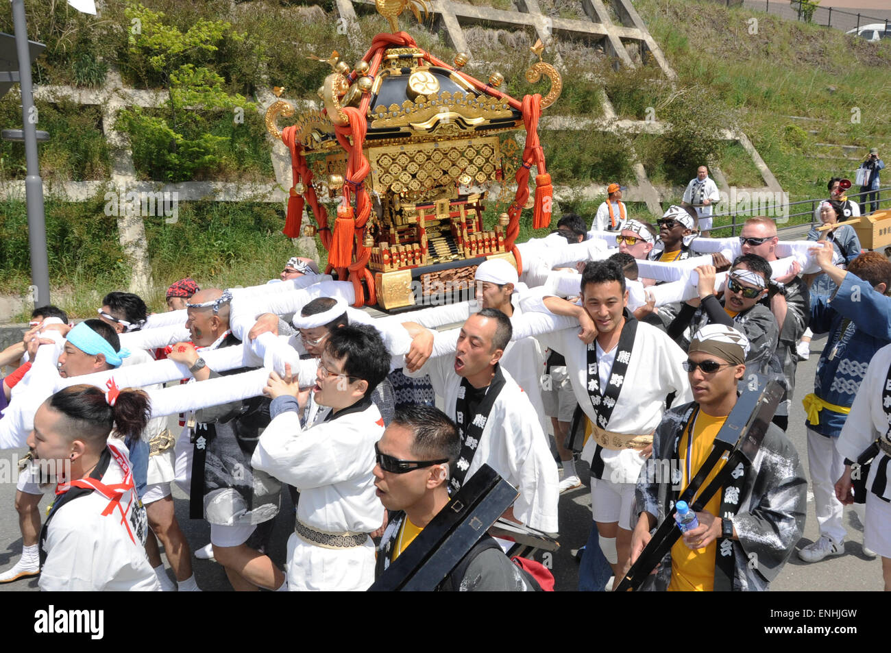 U.S. sailors join Japanese men carrying a Shinto shrine, called a mikoshi, to bring good luck to the city during the annual Mikoshi festival May 3, 2015 in Onagawa, Miyagi prefecture, Japan. The city of Onagawa was devastated by the earthquake and tsunami in 2011and began inviting the sailors to join in the festival to thank them for the assistance they provided following the disaster. Stock Photo