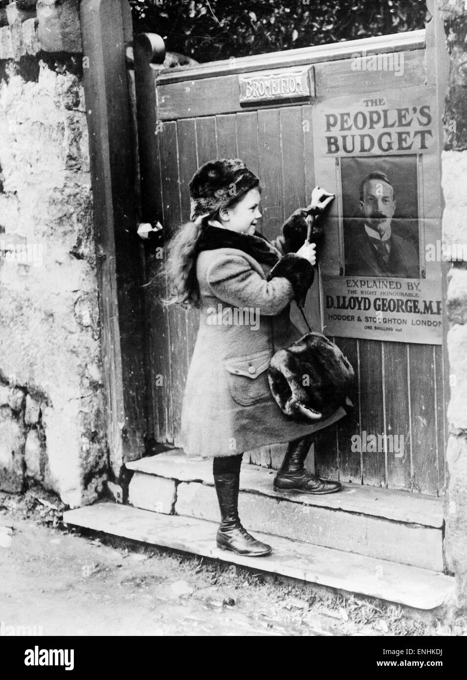 Lady Megan Lloyd George aged 8, fastens a People's Budget poster, featuring a portrait of her father David Lloyd George MP, onto the front of a gate in Wales, 15th January 1910. Stock Photo